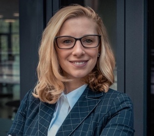 Nadja Hanusch stands in front of a building with her arms crossed and smiles...