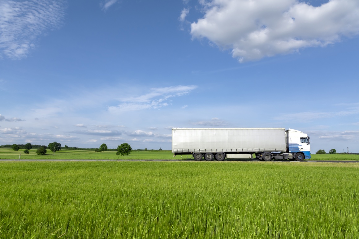 A truck driving through a green landscape.