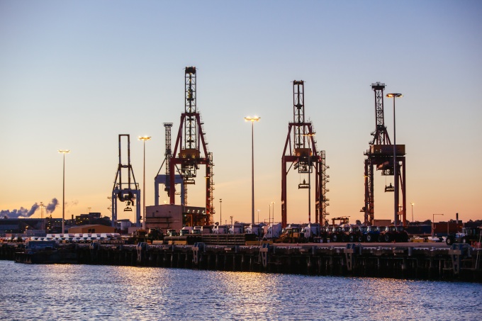 Man sieht einen Hafen mit 4 riesigen Kränen.