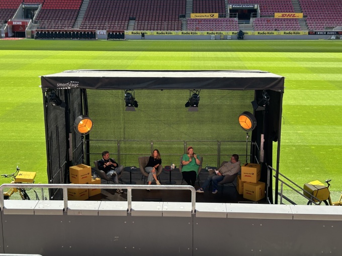 A stage in the RheinEnergieSTADION. There is a lively exchange taking place on...