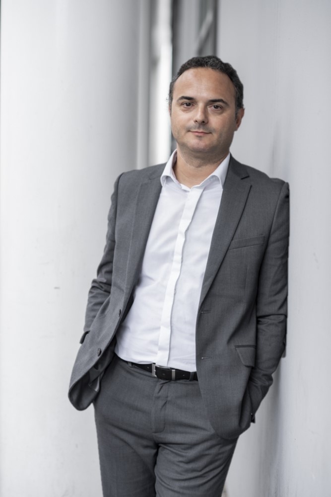 Man in a gray suit and white shirt leans against the wall and looks at the...