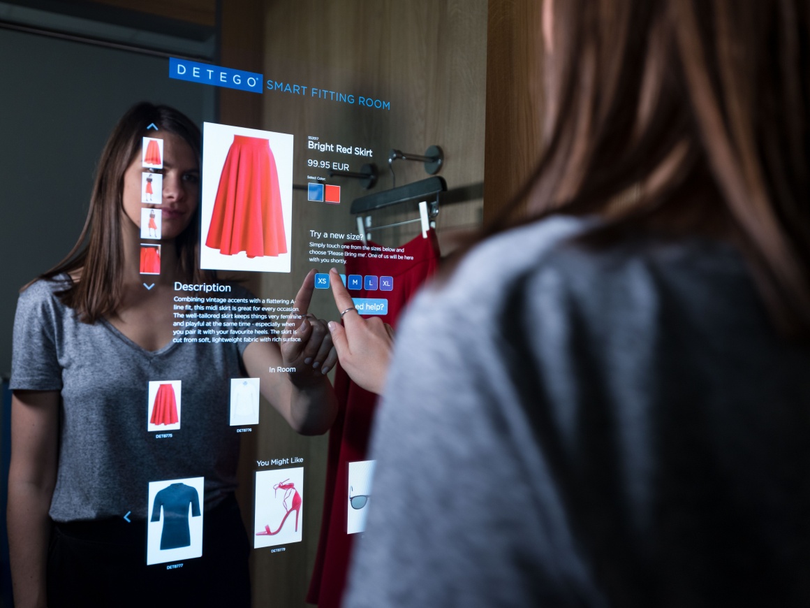 Photo: Woman using a digital touch screen in a dressing room; copyright: Detego...