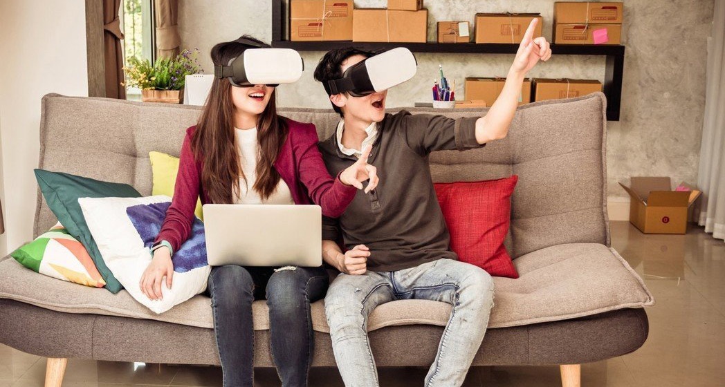 woman and man wearing virtual reality glasses on a sofa...