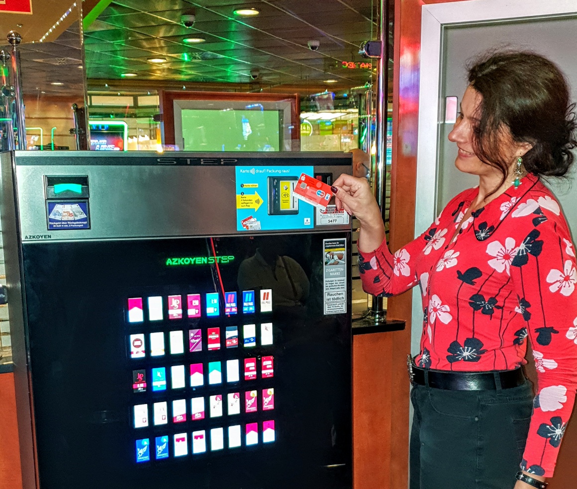 Frau hält Girocard an Terminal an Zigarettenautomat; copyright: Card4Vend...