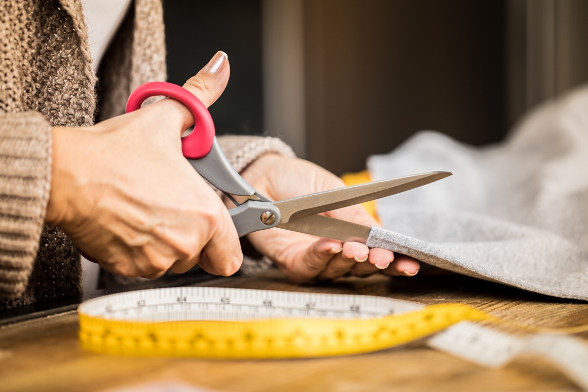 Tailor cutting fabric and measuring tape on the table; copyright:...