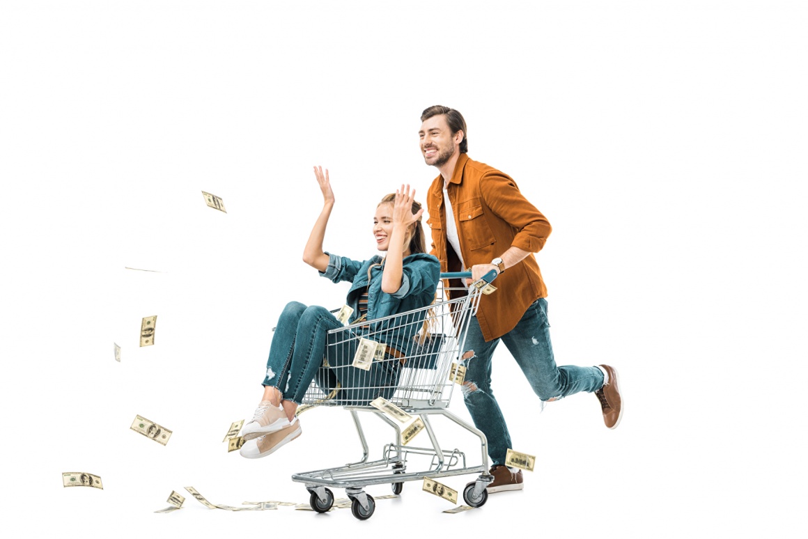 Woman sitting in a shopping cart driven by a man, throwing bank notes away;...