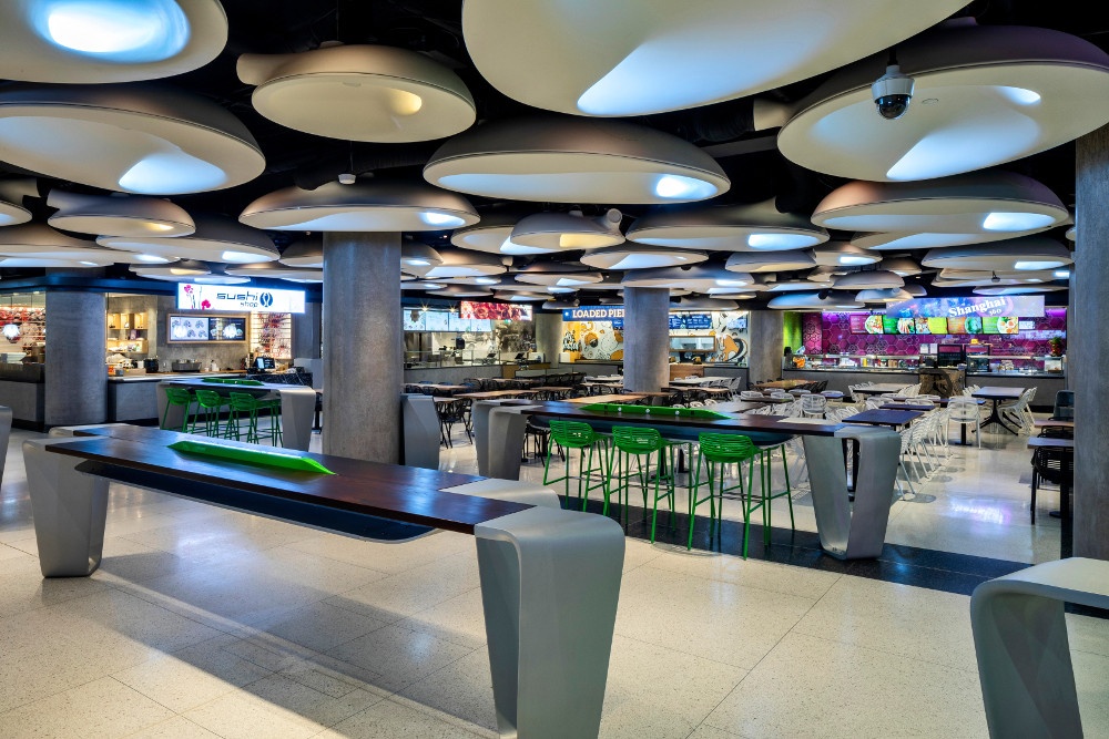 Empty food court with bars and tables and lighting installation at the ceiling;...