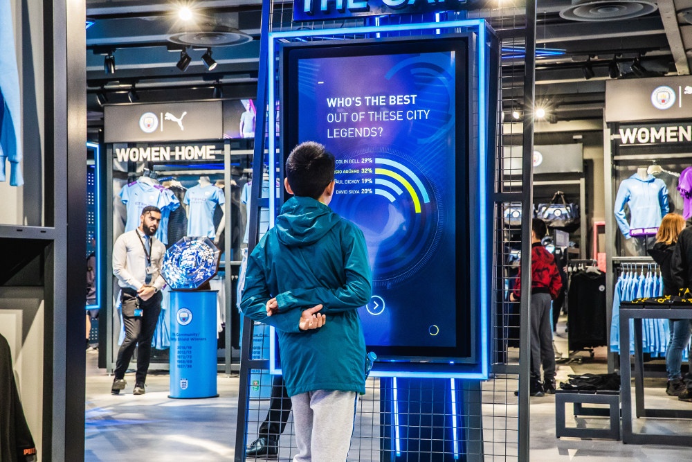 Boy standing in front of a digital screen in a sport’s store; copyright:...