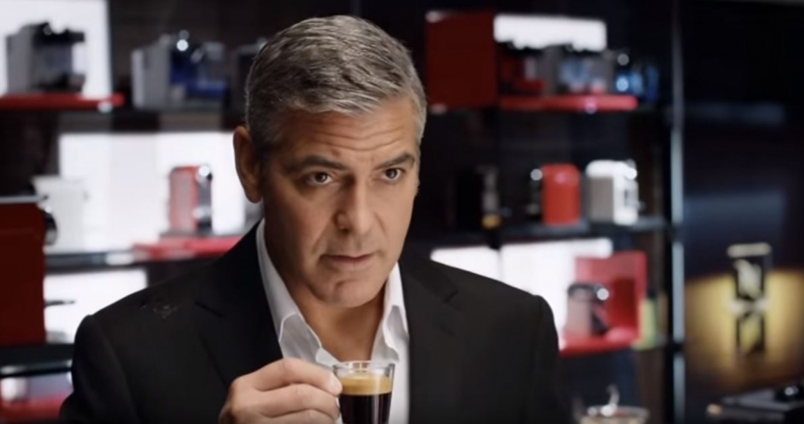 Actor George Clooney drinking espresso from a glass cup; screenshot of a...