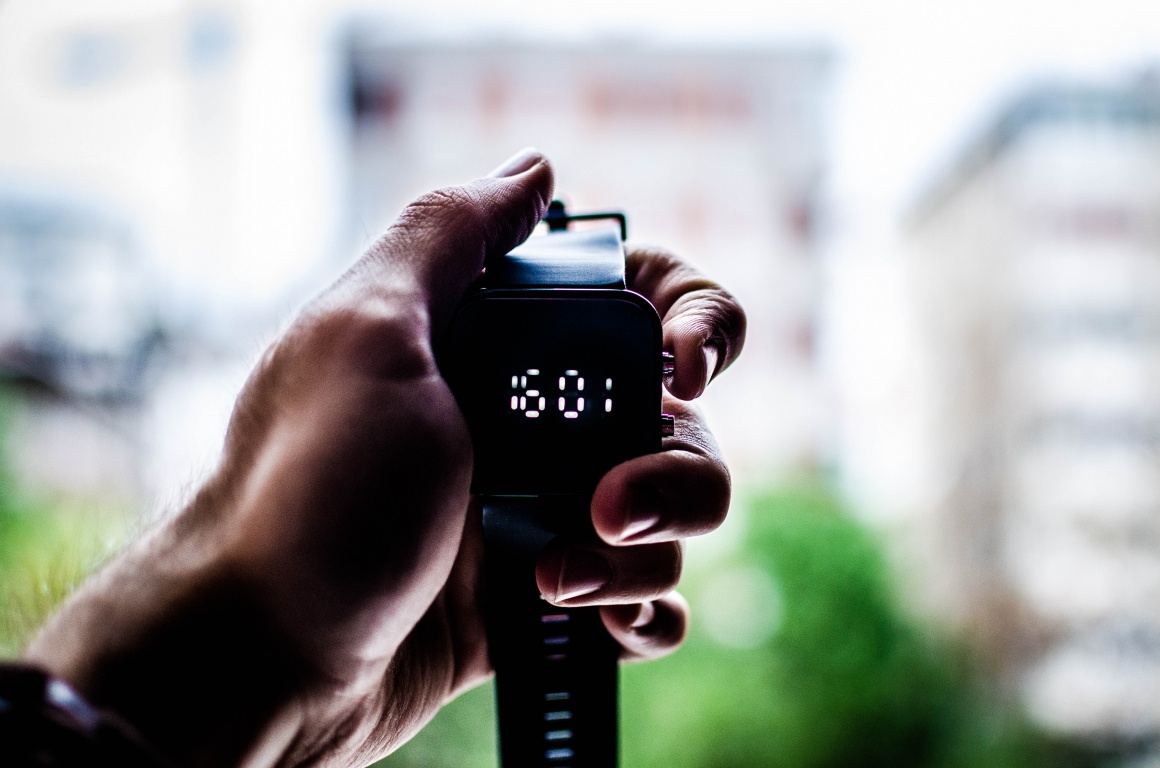 Hand holds digital black watch in the air