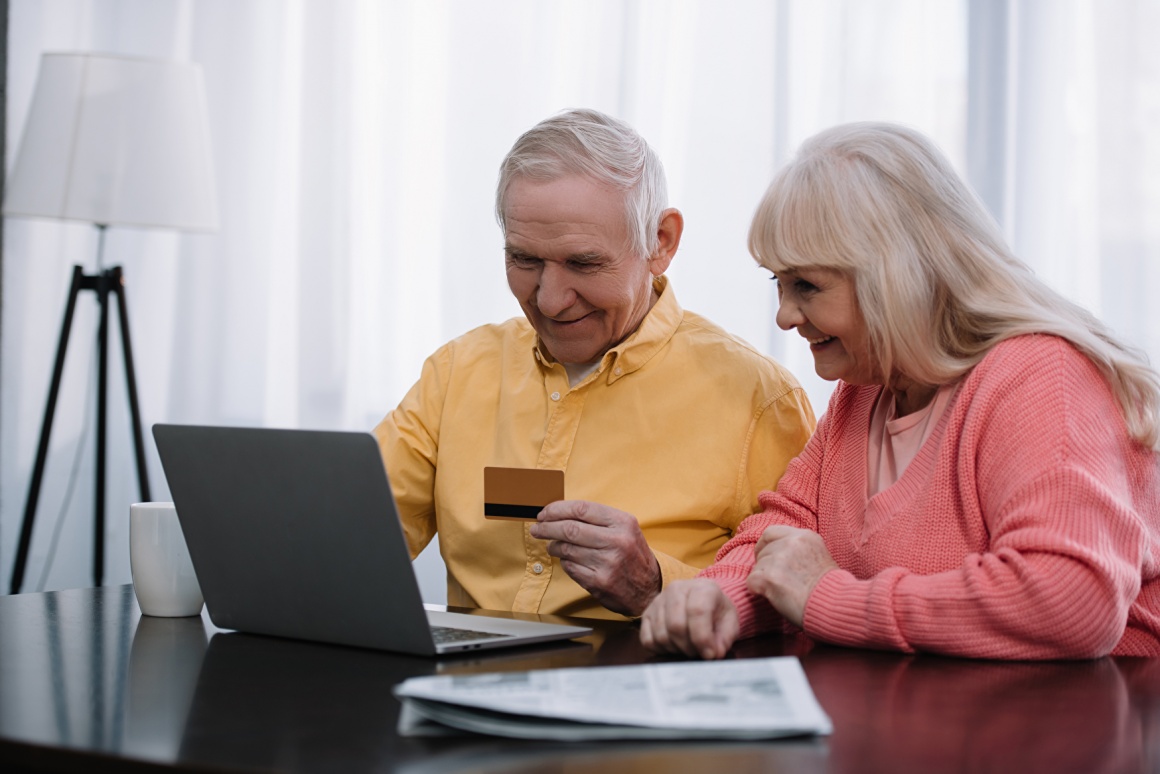Two seniors - man and woman - sitting in front of their laptop and shopping...