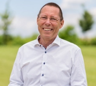 Man in jeans and white shirt standing in the meadow smiling into the camera...