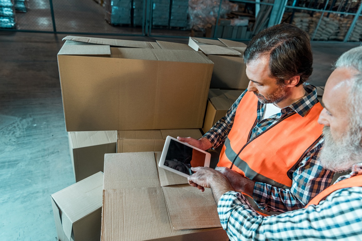 Two men working in logistics are using a tablet.