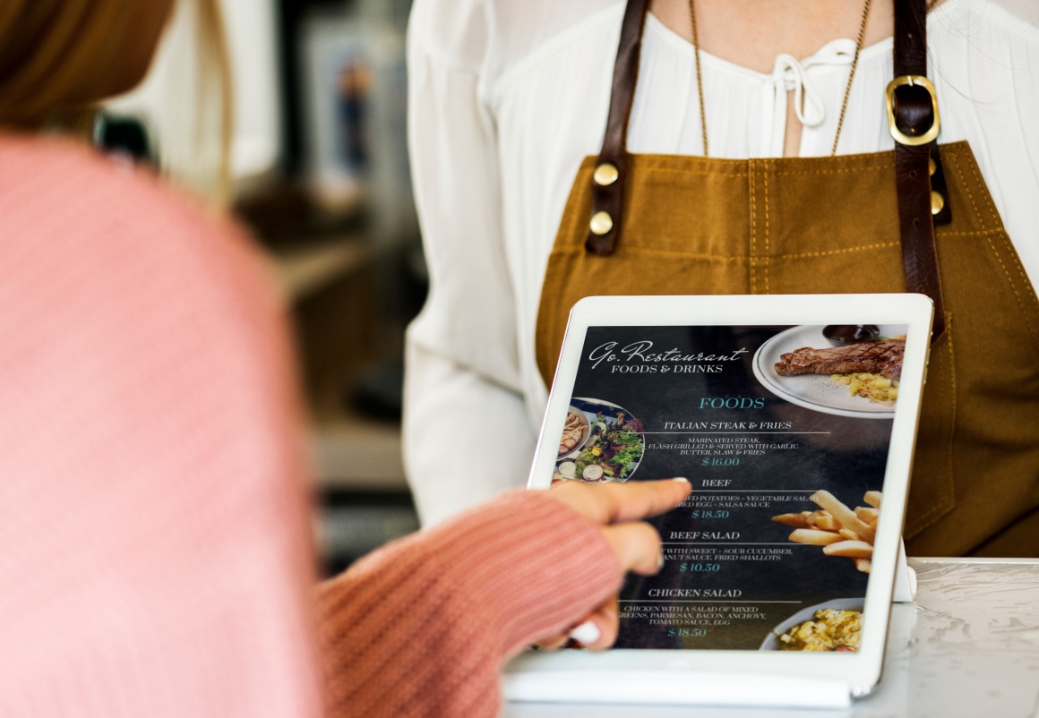 A customer taps on a tablet with a menu on it