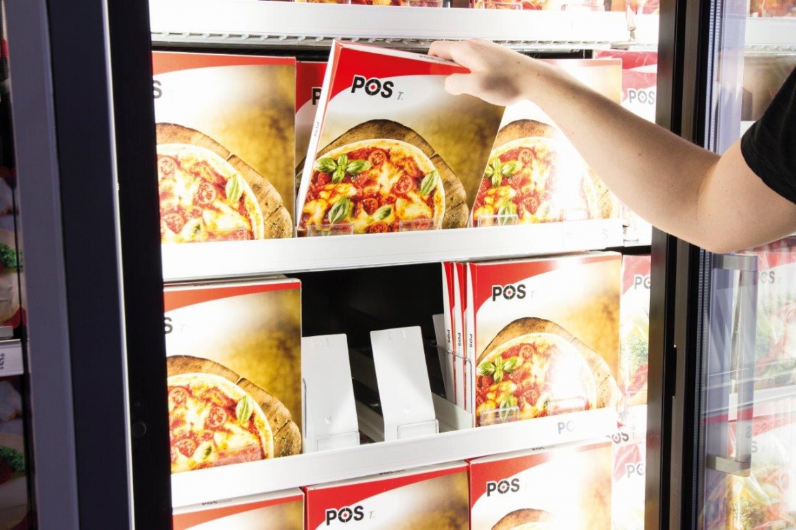 One hand grabs a frozen pizza from the chiller cabinet...