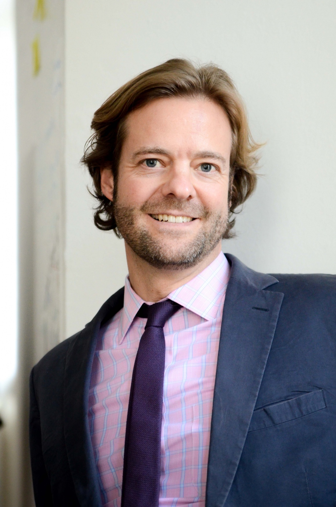 A man in a suit with a three-day beard and medium-length hair...