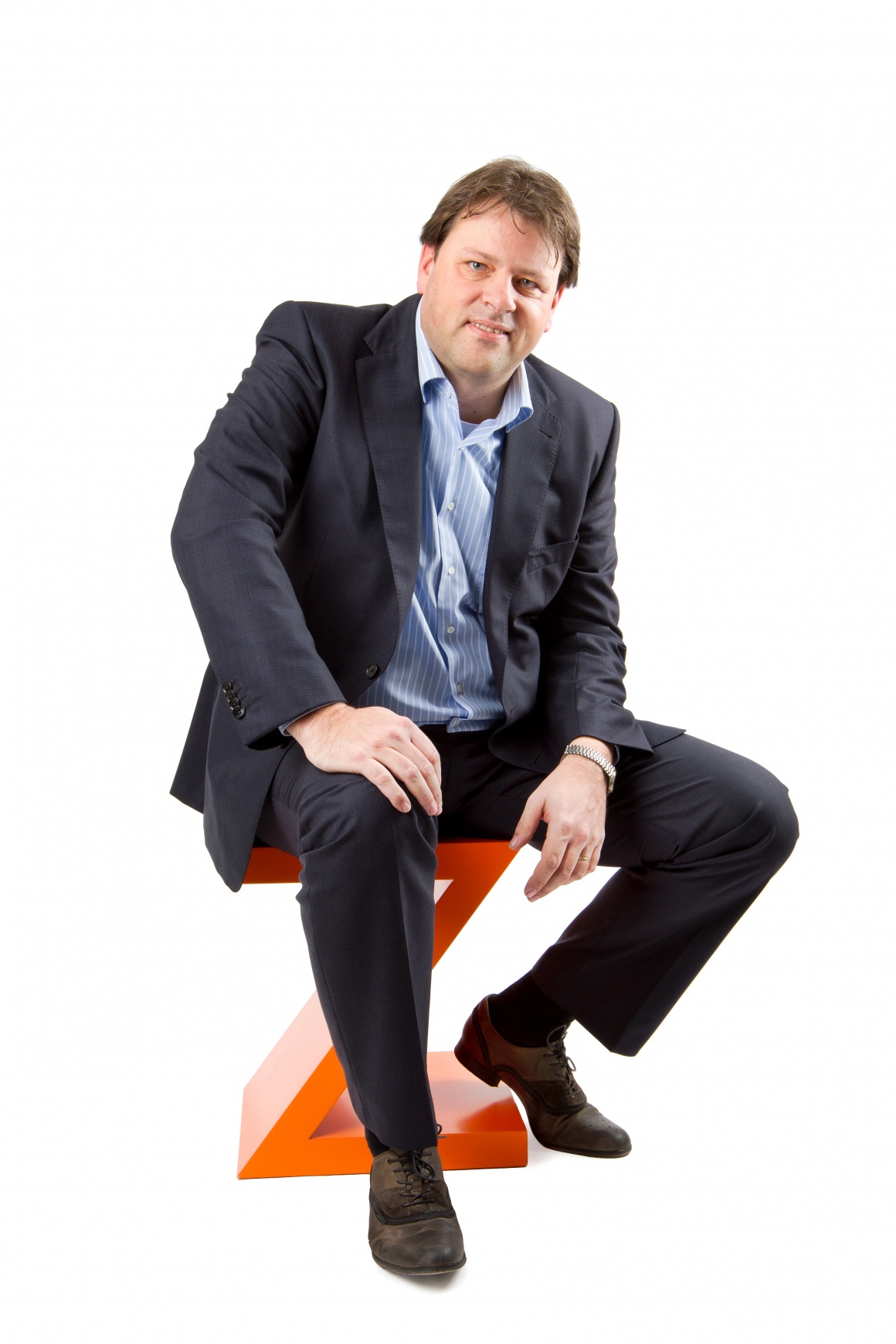 A man in a suit sitting on an orange Z
