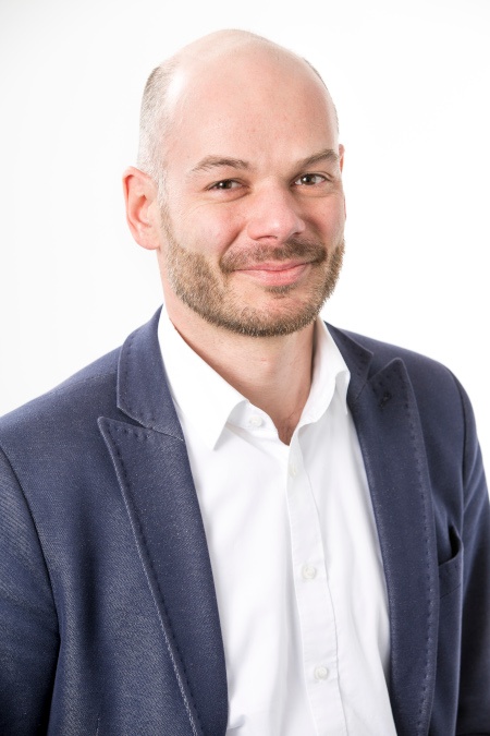 A man in a suit smiles at the camera