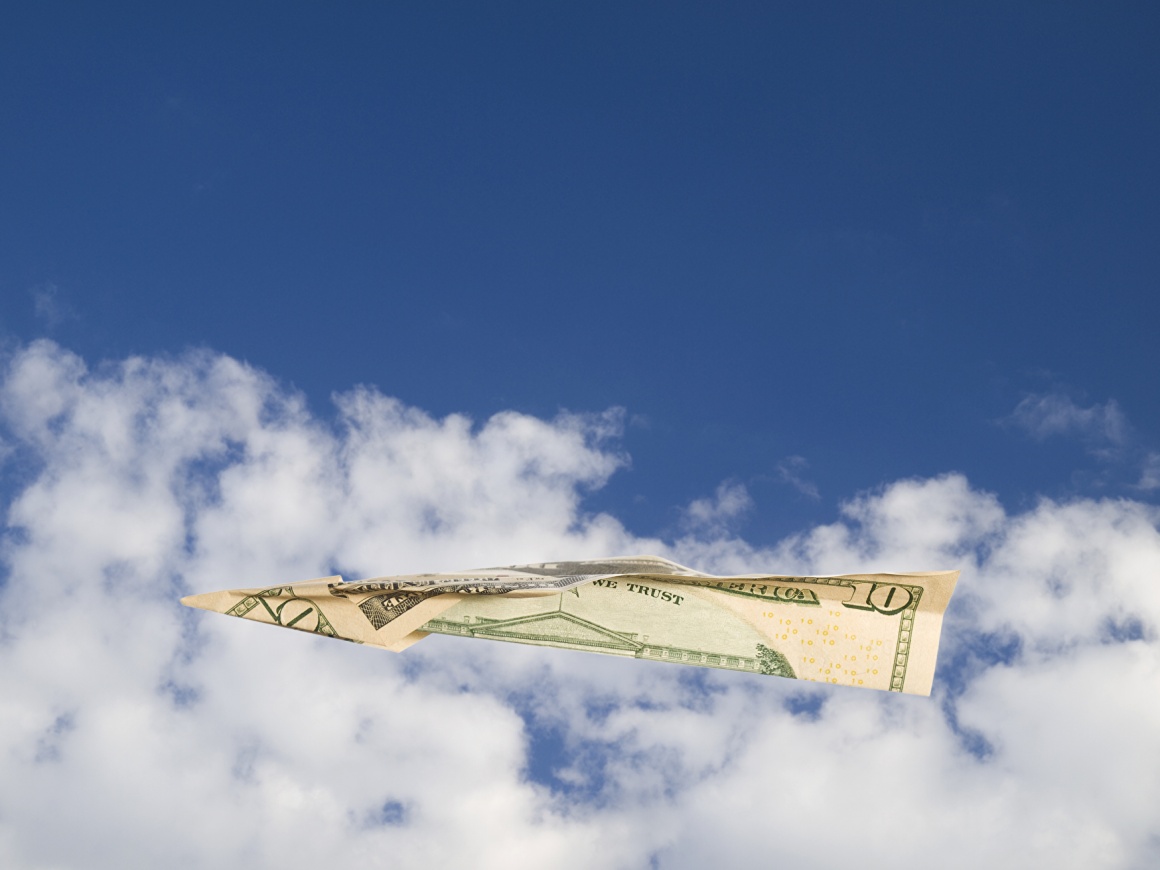A dollar note as a paper airplane flying through the cloudy sky...