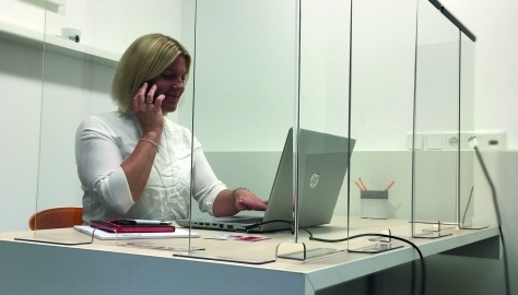 Woman in the office behind plexiglass windows
