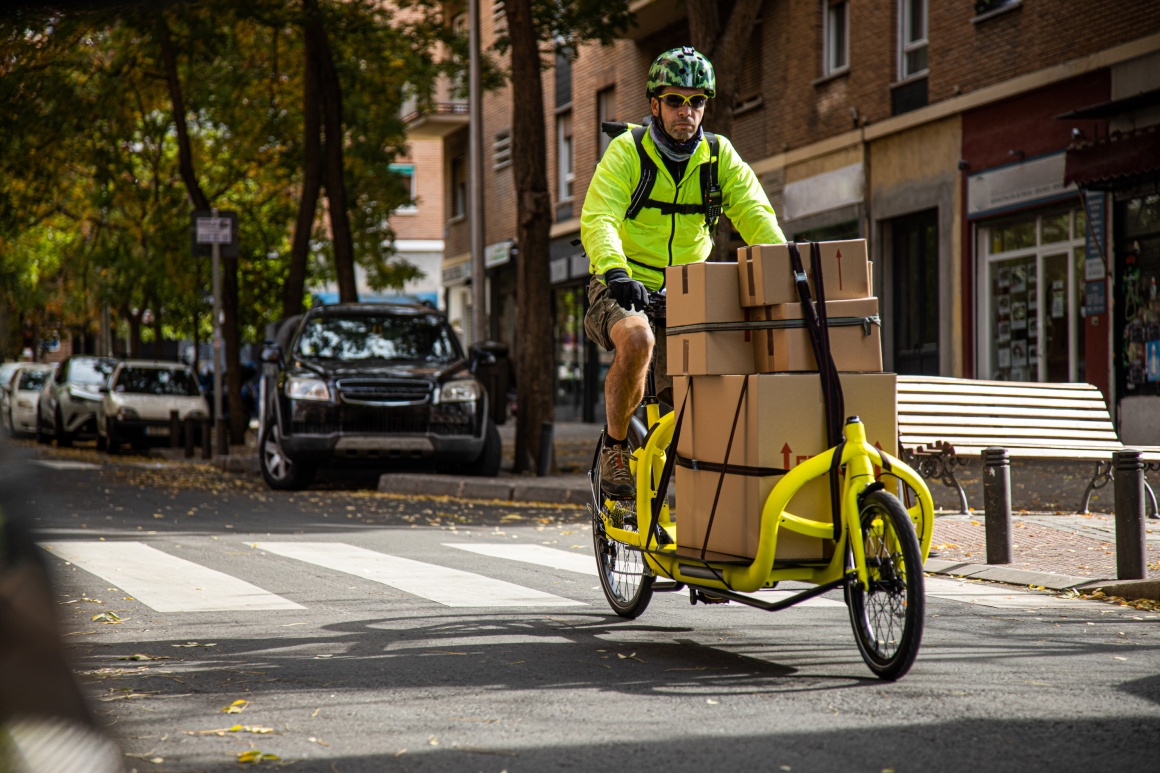 Bike courier, in green jacket on yellow bike and with helmet...