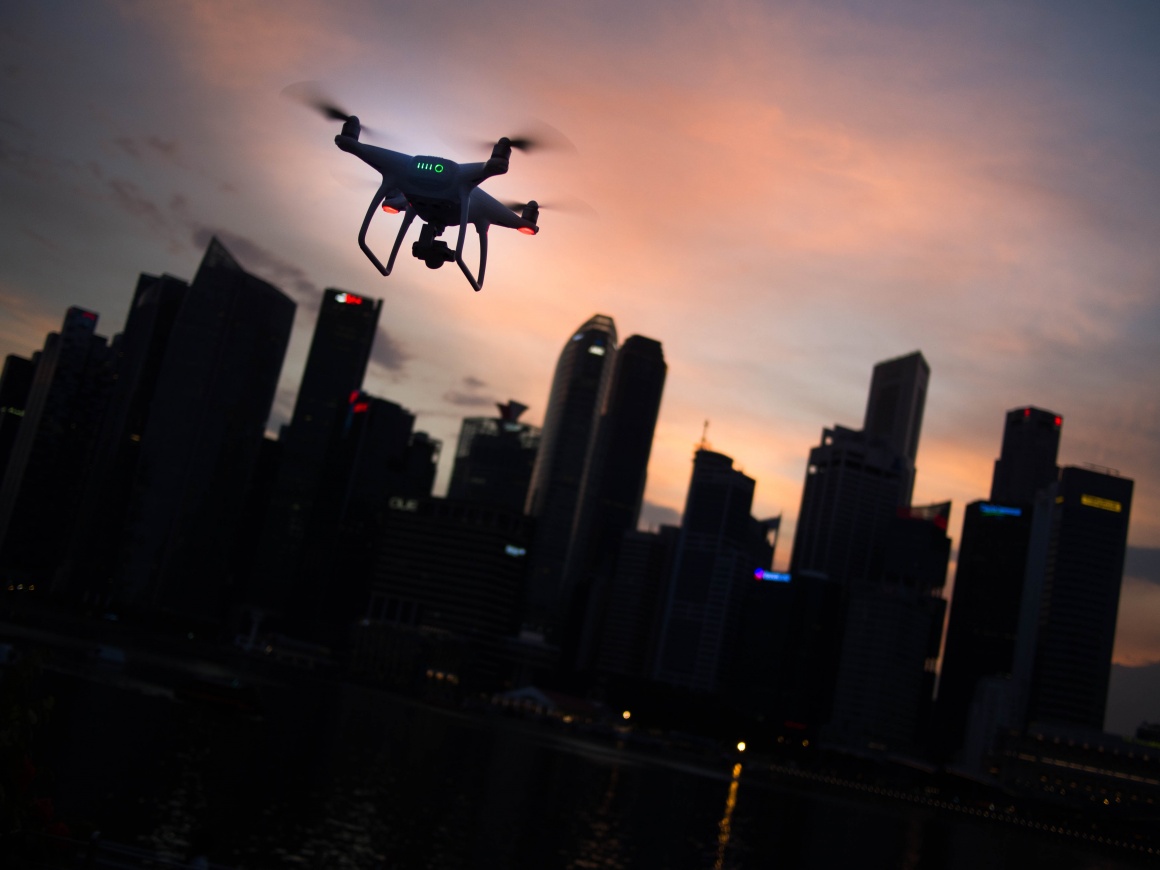 A drone in front of a dark city skyline