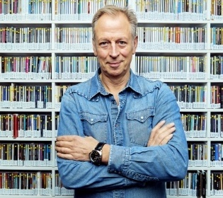 Man in blue shirt in front of CD shelf