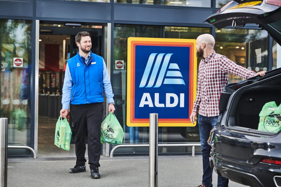 An Aldi employee carries a customers purchase to his car...