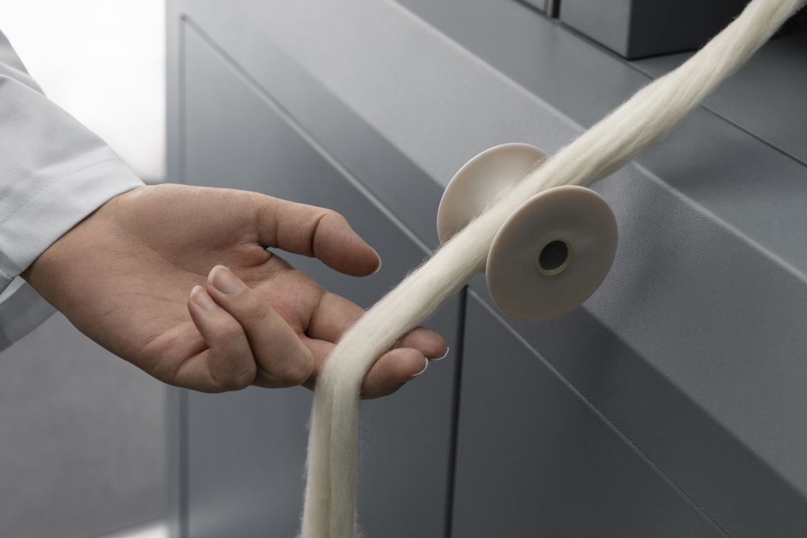 A thick string of old yarn comes out of a machine