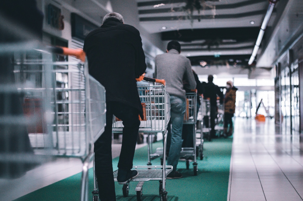 Several people standing in a line with shopping carts...