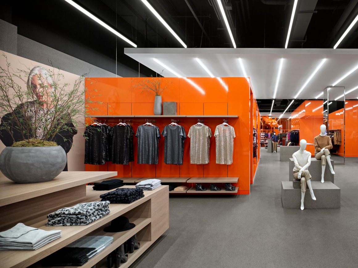 Interior of a flagship fashion store with bright orange furniture and grey...