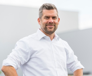 A man in a white shirt smiles at the camera