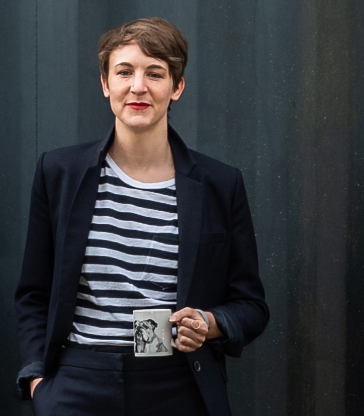 A woman in a blazer smiles at the camera