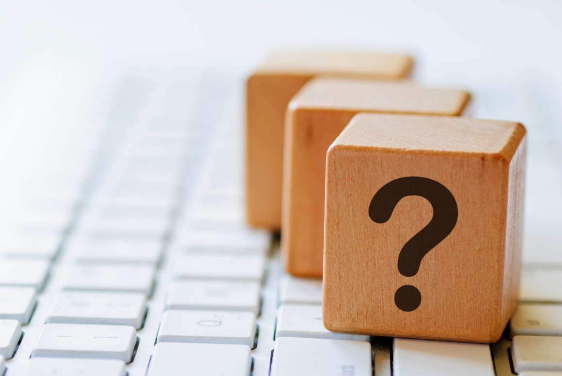 Three wooden dices with question marks on a computer keyboard...