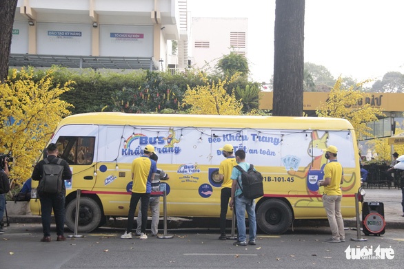 A yellow bus on a street and people standing around it; copyright: DONY Garment...