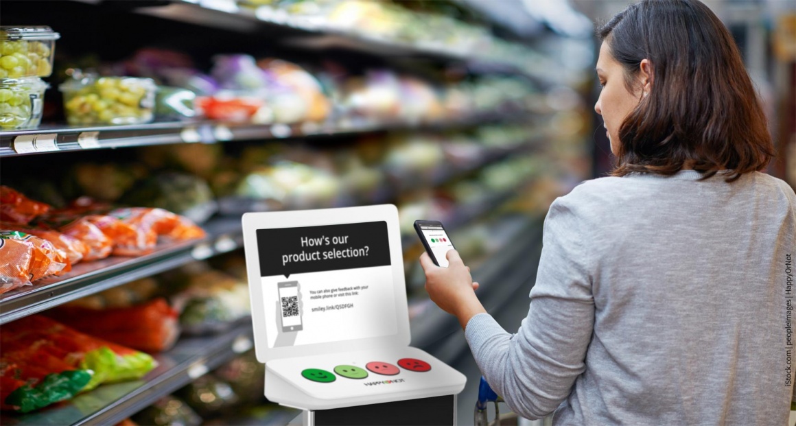 Woman in grocery store in front of feedback touch point...