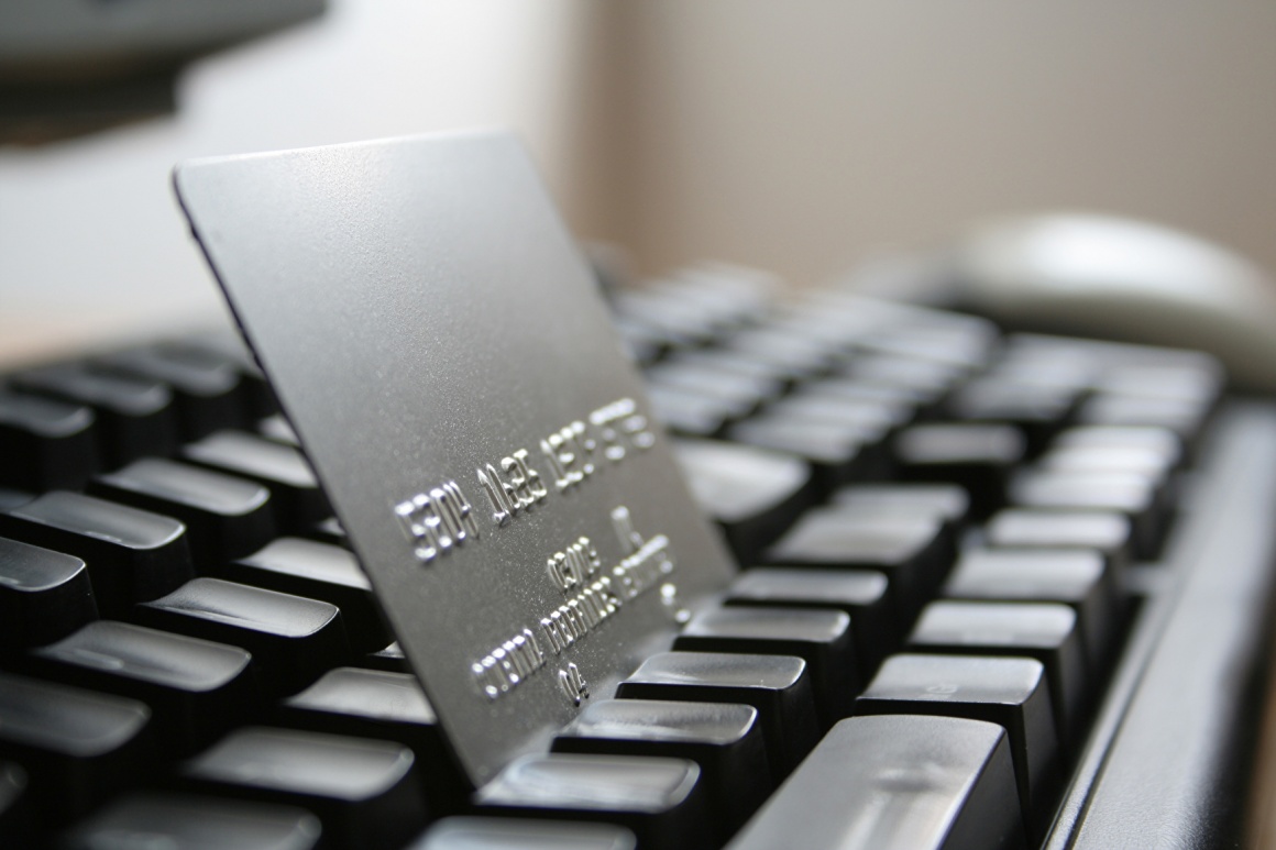 A silver credit card is standing between the buttons of a laptop keyboard...
