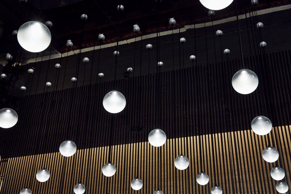 Many lamps hanging from a long cable from a black ceiling...