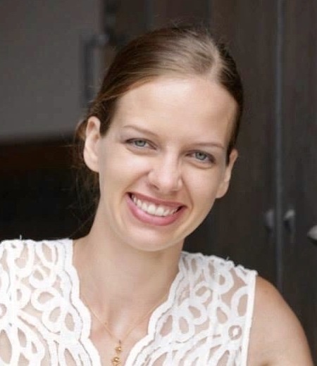 Woman wearing a white blouse smiles at the camera