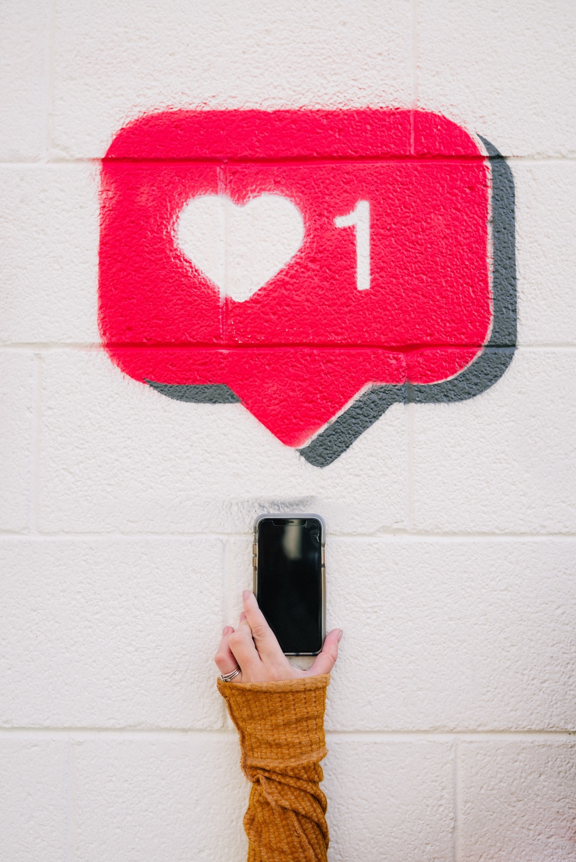 One hand holds up a smartphone, above it a pink speech bubble with a white...