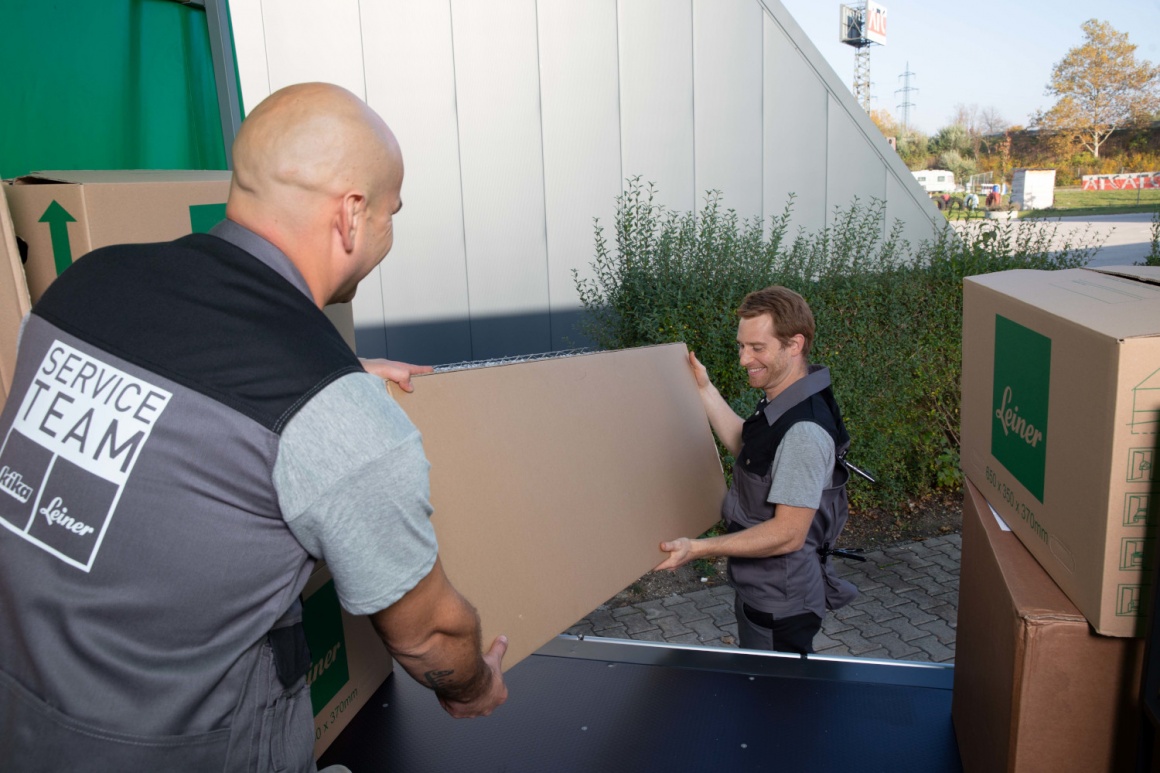 Two men transporting furniture lift a board out of a van...