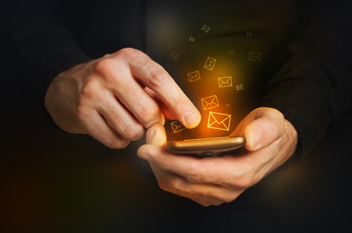 Man in black shirt is typing a text message on his smartphone close up image...