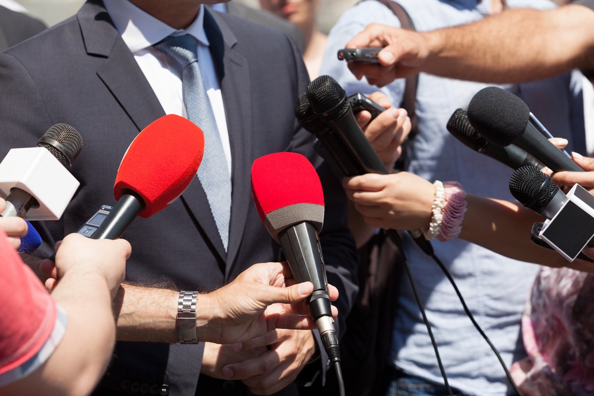 many microphones are pointed at a man who is giving an interview...