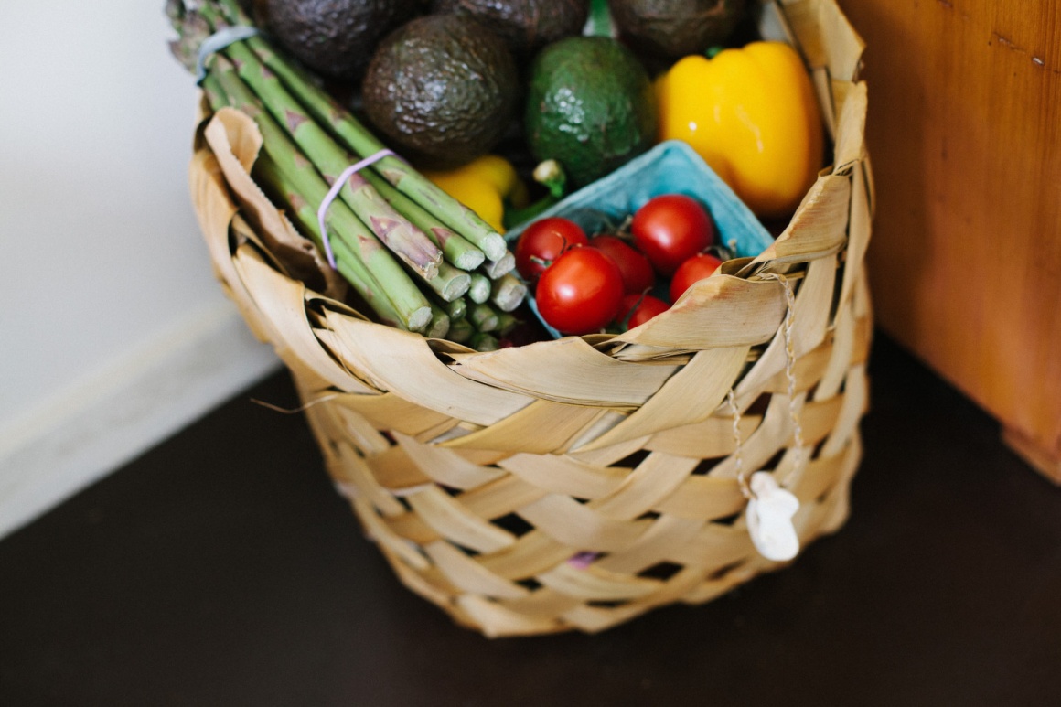 A basket in a corner full of fresh foods, vegetables and fruit...